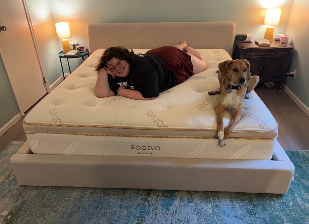 Kinsley Searles lying on a Saatva HD mattress with her dog. 